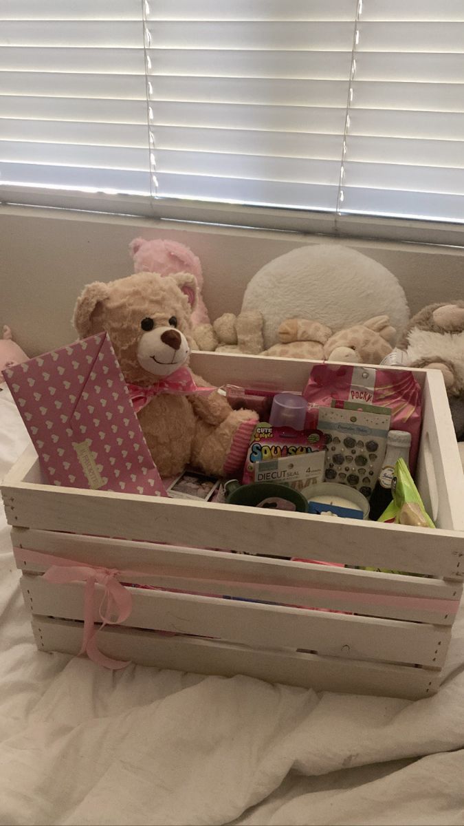 a teddy bear sitting in a wooden crate filled with baby goods and other stuff items