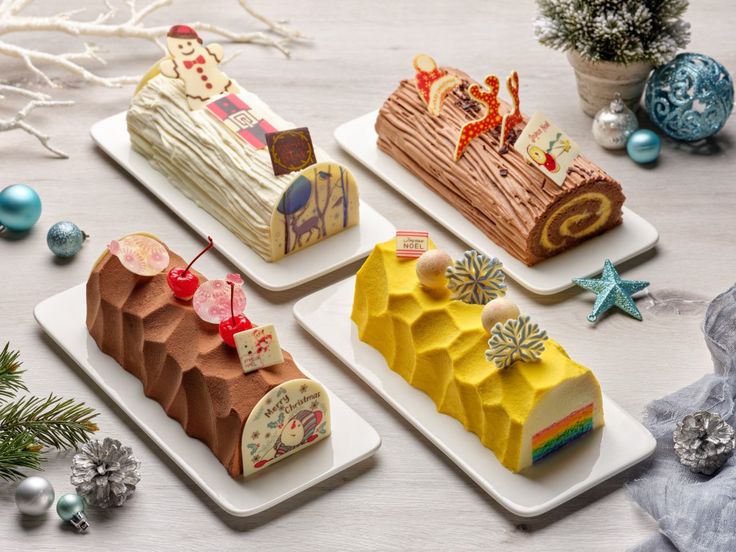 four different types of cakes on plates with christmas decorations around the edges and behind them