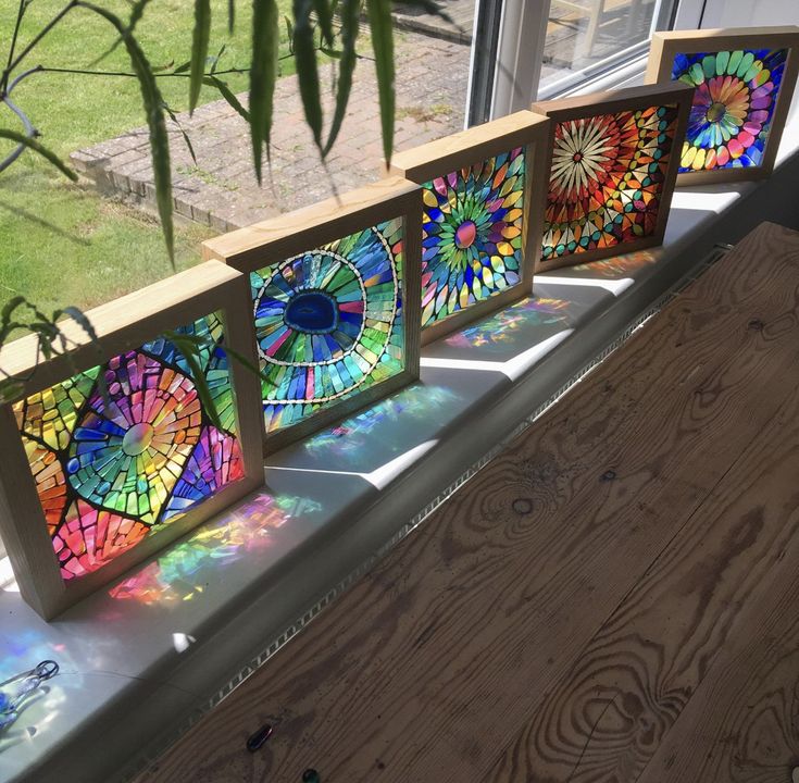 three stained glass pieces sitting on top of a window sill