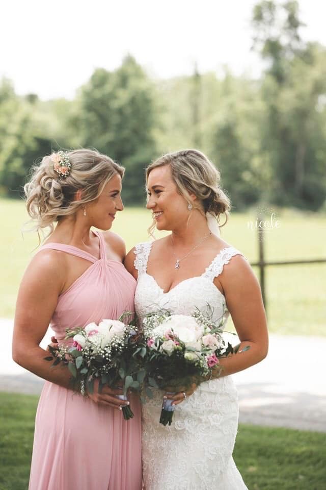 two women in dresses standing next to each other with bouquets on their heads and smiling