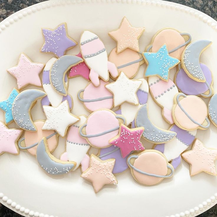 a plate full of decorated cookies with stars and moon on them in pastel colors