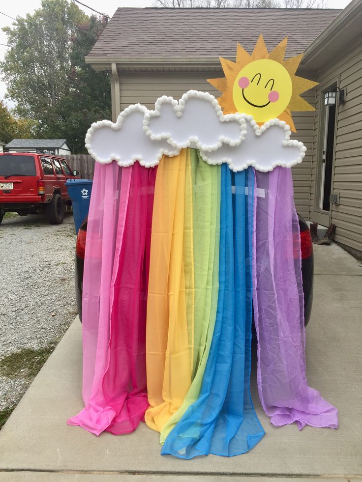 there is a rainbow decoration in front of a house with a sun on the cloud