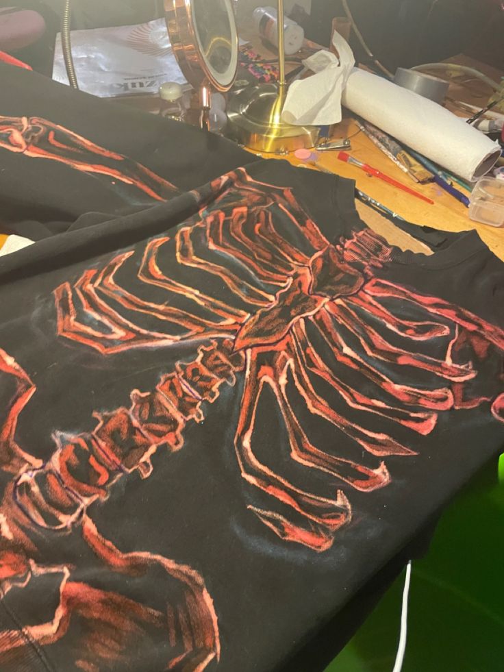 a table topped with a black cloth covered in red and orange skeleton designs on it