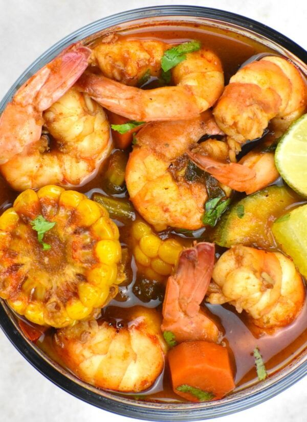 a bowl filled with shrimp and vegetables next to a slice of lime