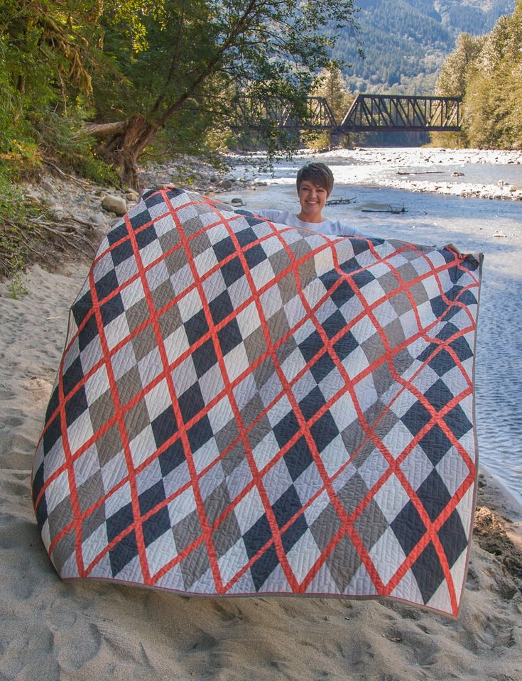 a man holding up a quilt on the beach