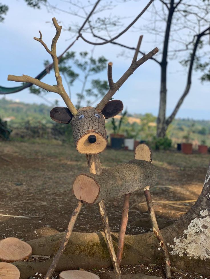 a deer made out of wood sitting on top of a pile of tree trunks and logs