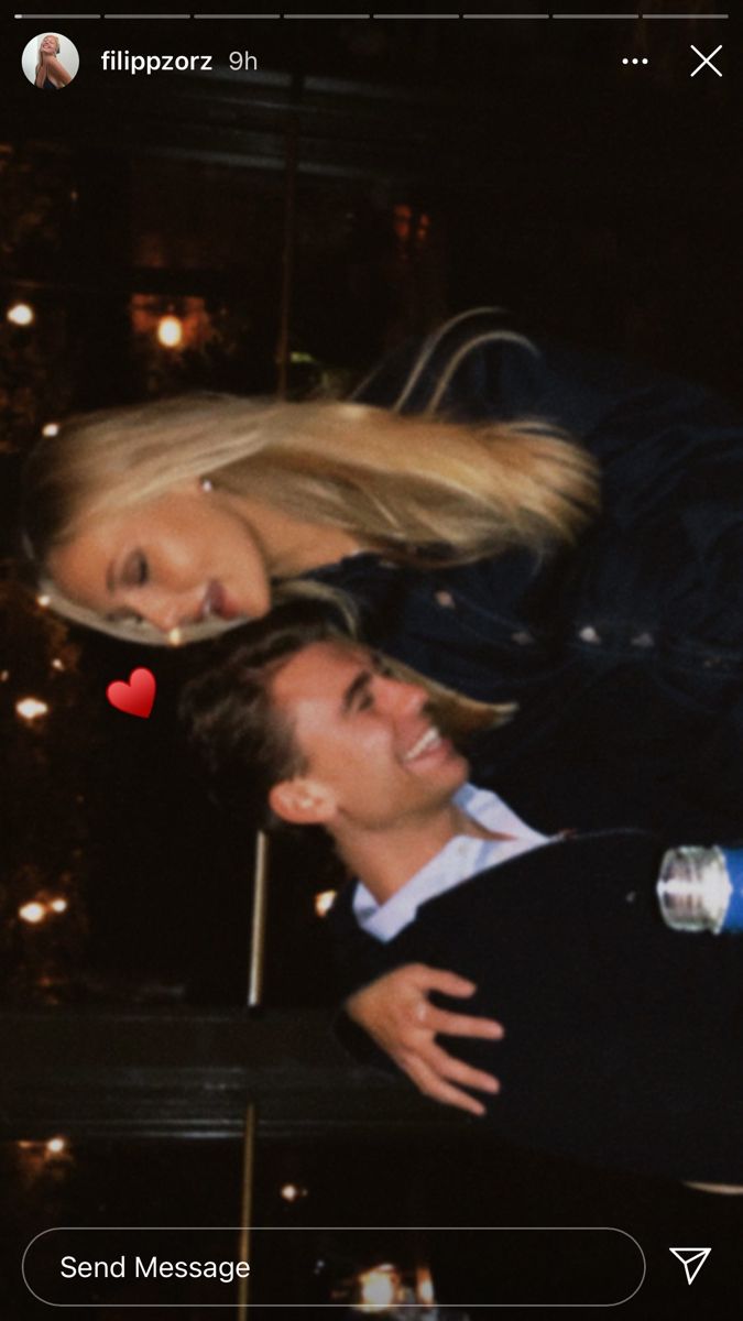 a man and woman standing next to each other in front of a christmas tree at night