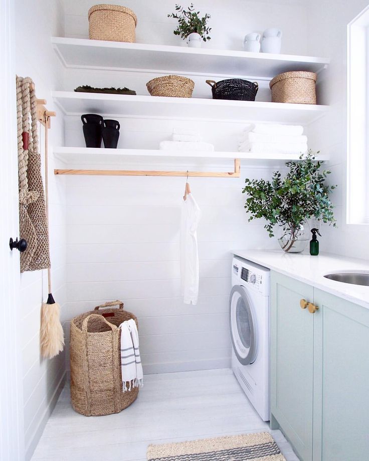 a washer and dryer in a white laundry room with open shelving on the wall