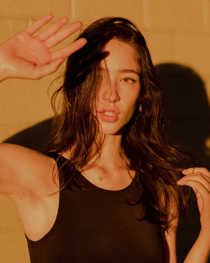 a woman with long hair is posing for the camera while holding her hand up to her head