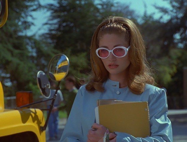 a woman wearing pink sunglasses and holding a folder