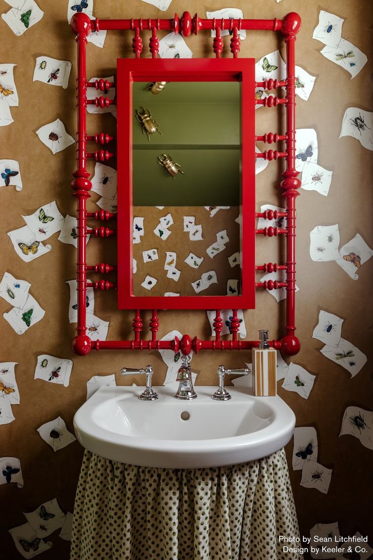 a bathroom sink sitting under a red framed mirror