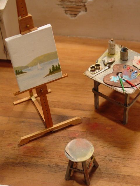 a miniature easel with paint and an artist's palette sitting on the floor