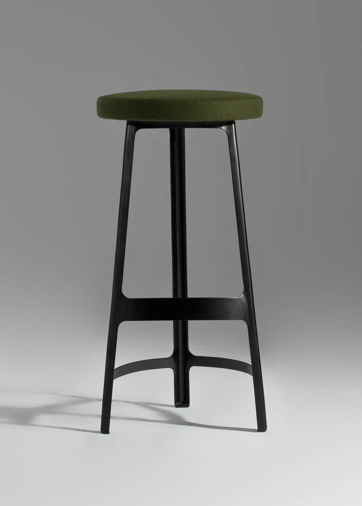 a black stool with a green seat on a gray background and a shadow from the floor