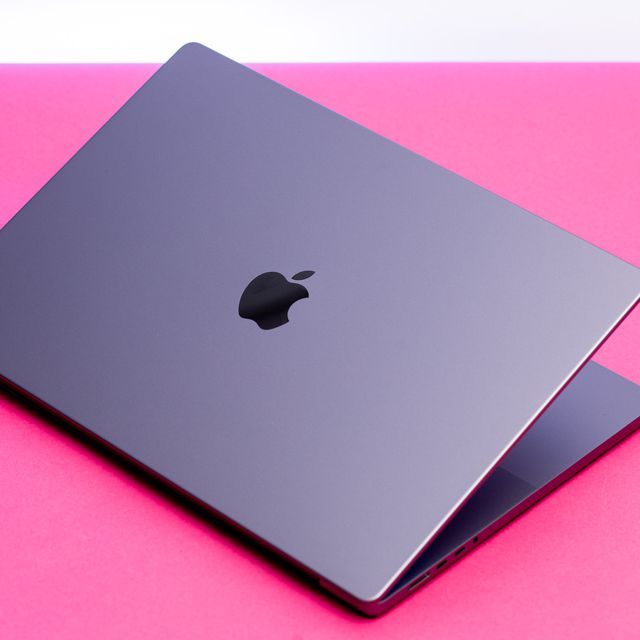 an apple laptop computer sitting on top of a pink surface