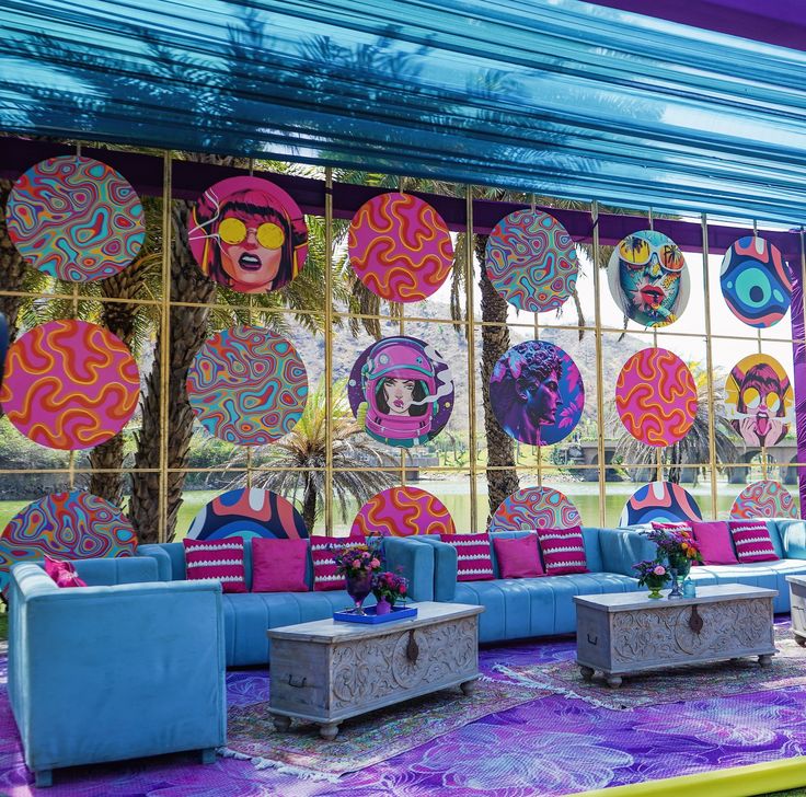 an outdoor lounge area with blue couches and colorful artwork on the wall