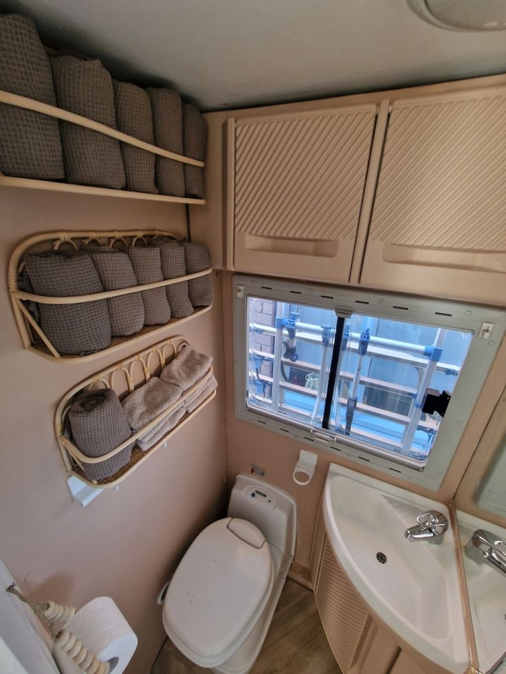 a small bathroom with a toilet, sink and shelves on the wall next to it