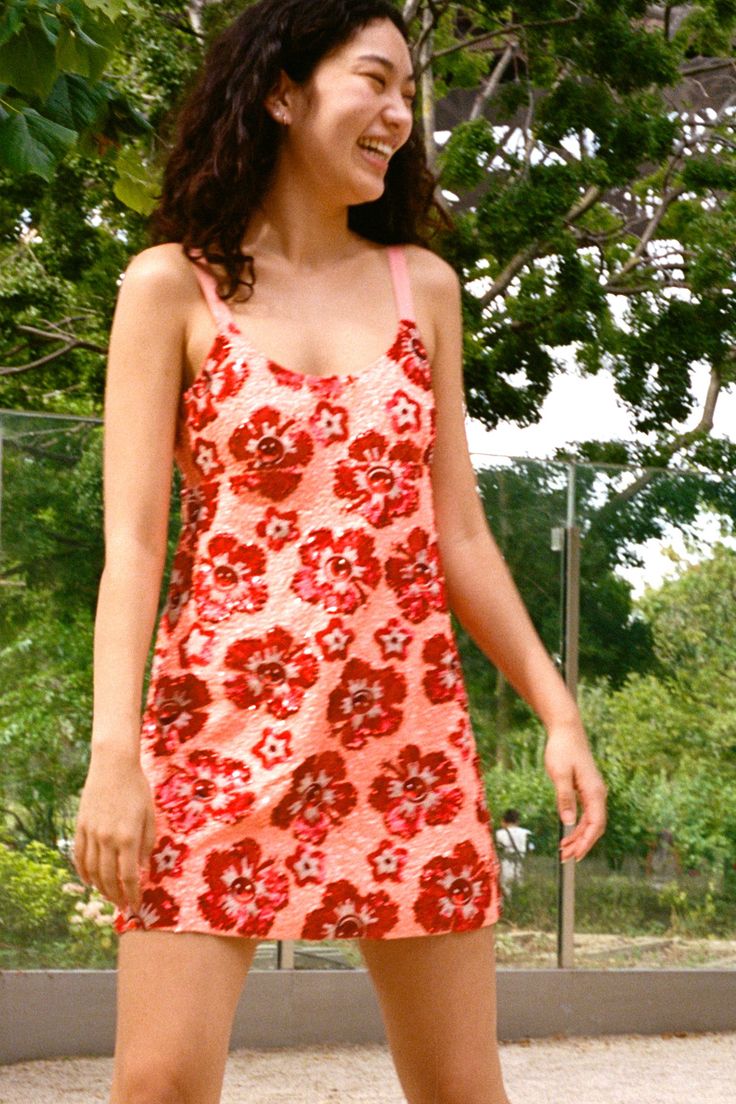 a woman riding a skateboard on top of a cement ground with trees in the background