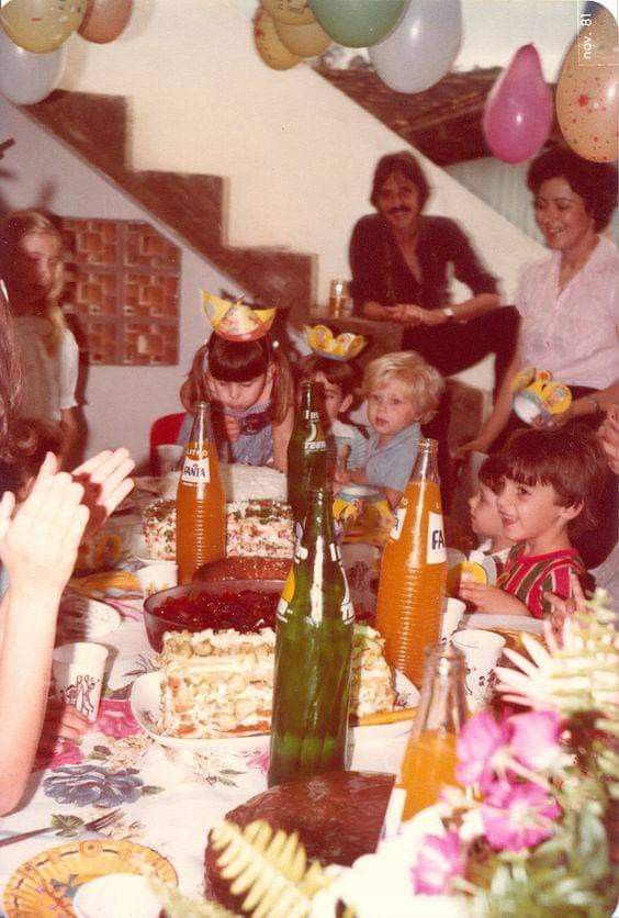 a group of people sitting around a table with food and drinks