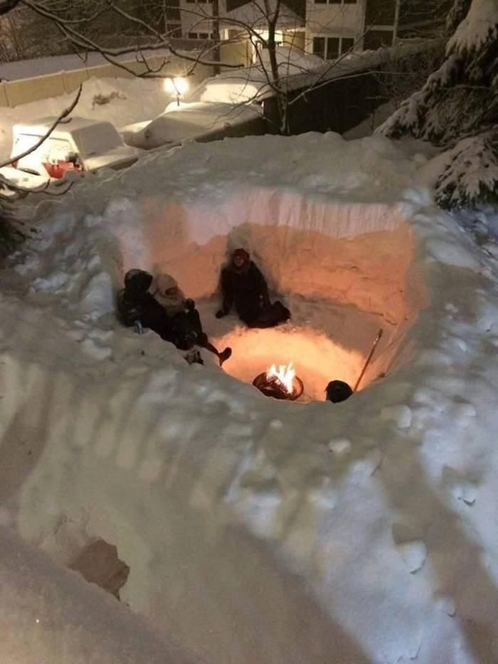 two people are sitting in the middle of an open fire pit with snow on it