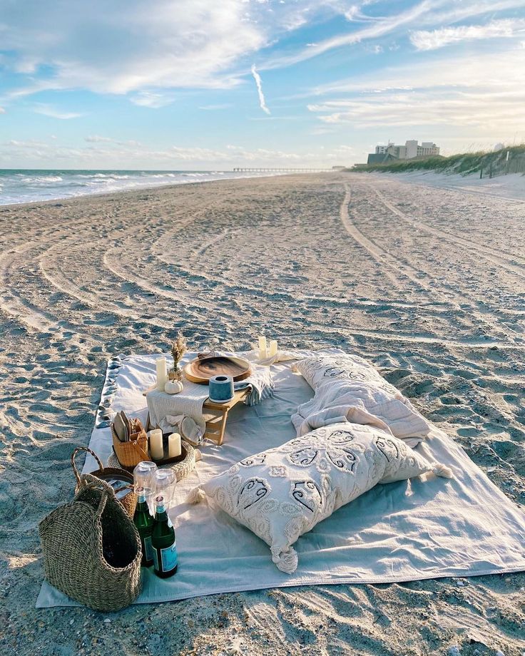 a picnic on the beach is set up with food and drinks in front of the ocean