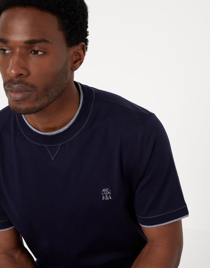 Cotton jersey crew neck T-shirt with logo and faux-layering Refined details enhance this classic crew-neck T-shirt in soft cotton jersey from the Travelwear line, dedicated to moments of relaxation and free time. The contrasting inserts create a layered effect that highlights the edge of the crew-neck, sleeves and bottom, while the Solomeo crest on the chest references the origins and values of the brand. The silhouette features regular proportions. Classic Crew Neck Tops With Embroidered Logo, Classic Crew Tops With Embroidered Logo, Classic Crew Top With Embroidered Logo, Classic Crew Neck T-shirt With Embroidered Logo, Sporty Crew Neck Top With Contrast Stitching, Classic Short Sleeve Tops With Logo Detail, Sporty Crew Neck T-shirt For Layering, Sporty Crew Neck T-shirt With Logo, Casual Crew Neck T-shirt With Logo