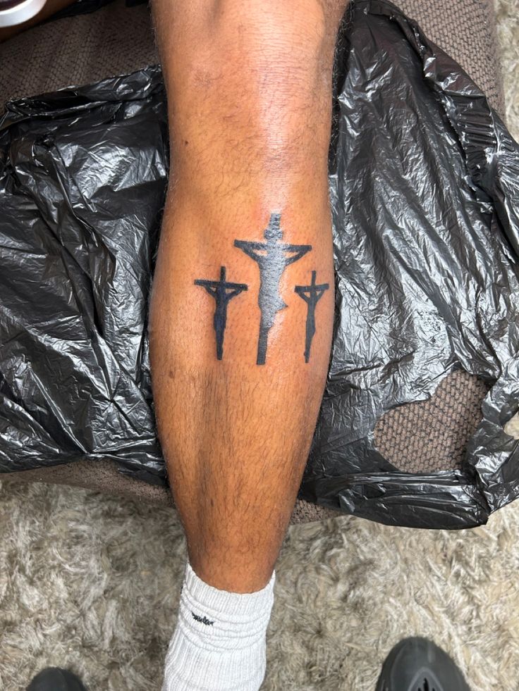 a man's leg with three crosses tattooed on it