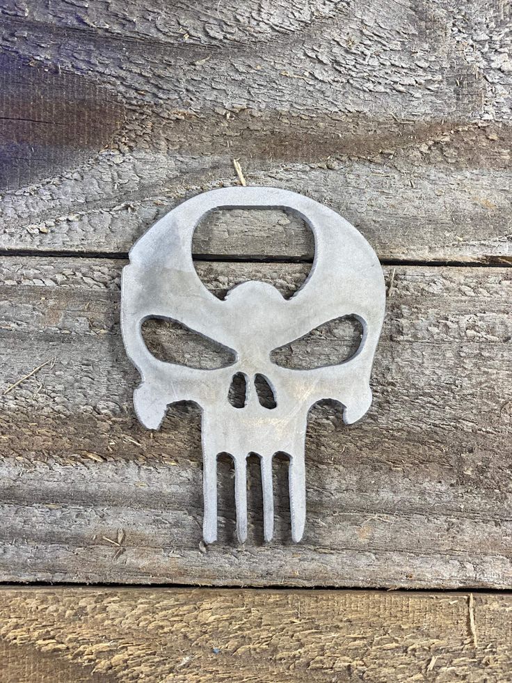 a skull shaped metal object sitting on top of a wooden table next to a wall