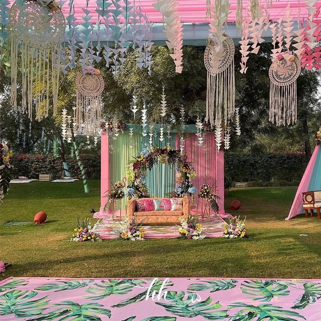 an outdoor wedding setup with pink and blue decor on the grass, hanging from ceiling