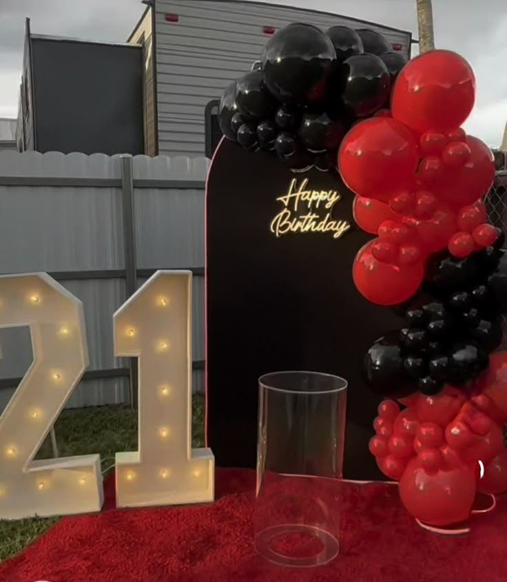 the table is set up with balloons, candles and a 21st birthday sign on it