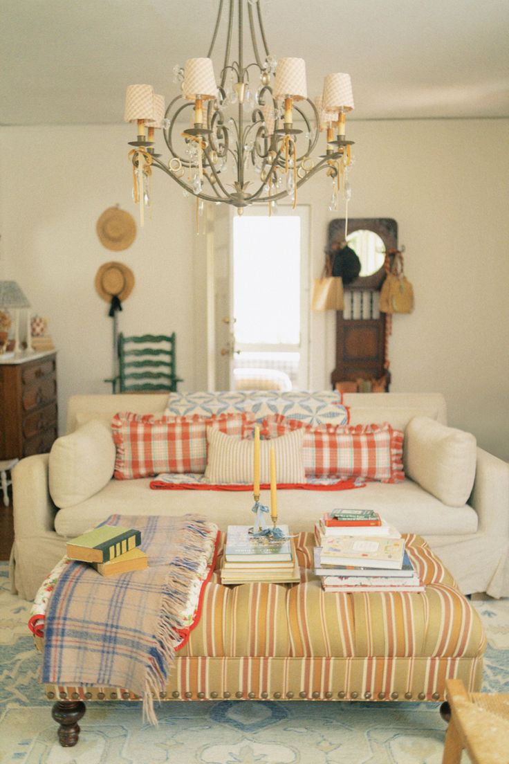 a living room filled with furniture and a chandelier hanging over the top of it