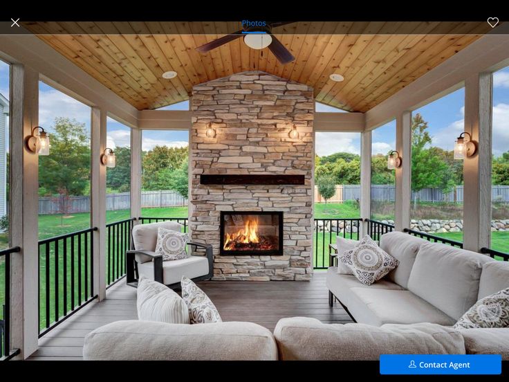 a covered porch with couches and a fire place