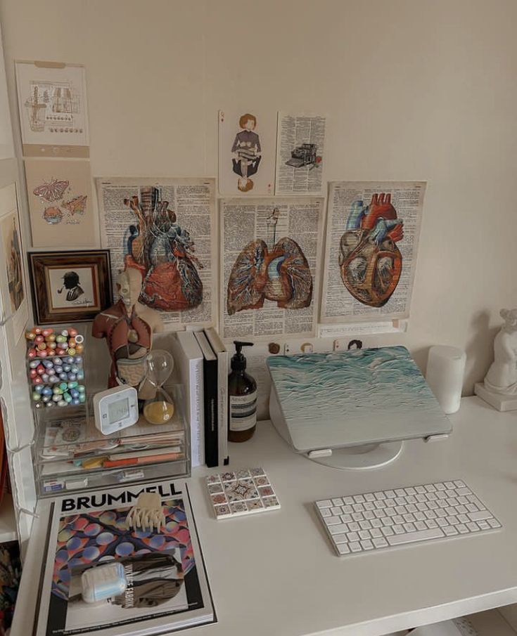 a white desk topped with lots of different types of art and books on top of it