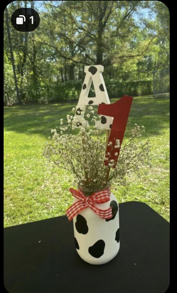 a vase filled with flowers sitting on top of a table in front of a grass covered field