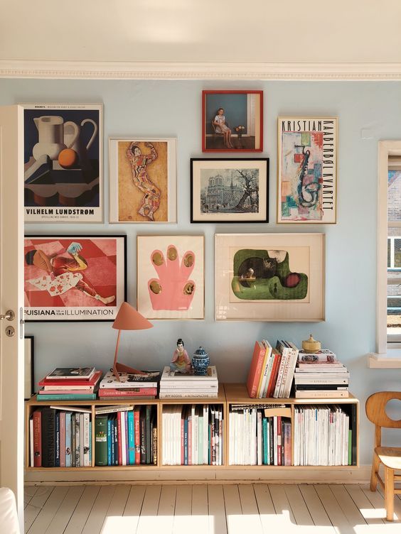 a room with many pictures on the wall and bookshelves in front of it