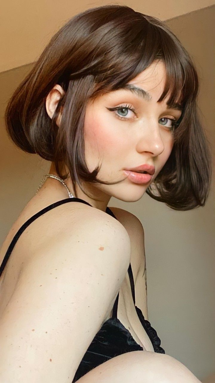 a woman with short hair wearing a halter top and black bra posing for the camera