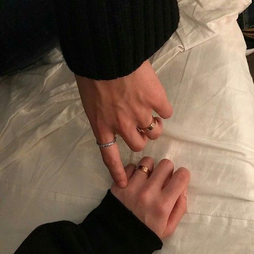 two people holding hands on top of a white sheet with their fingers touching each other