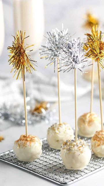 some cake pops are on a cooling rack with gold and silver sprinkles