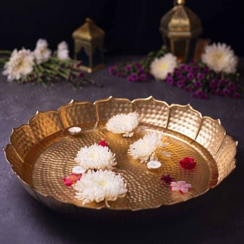 a gold plate with flowers on it sitting next to some candles and vases in the background