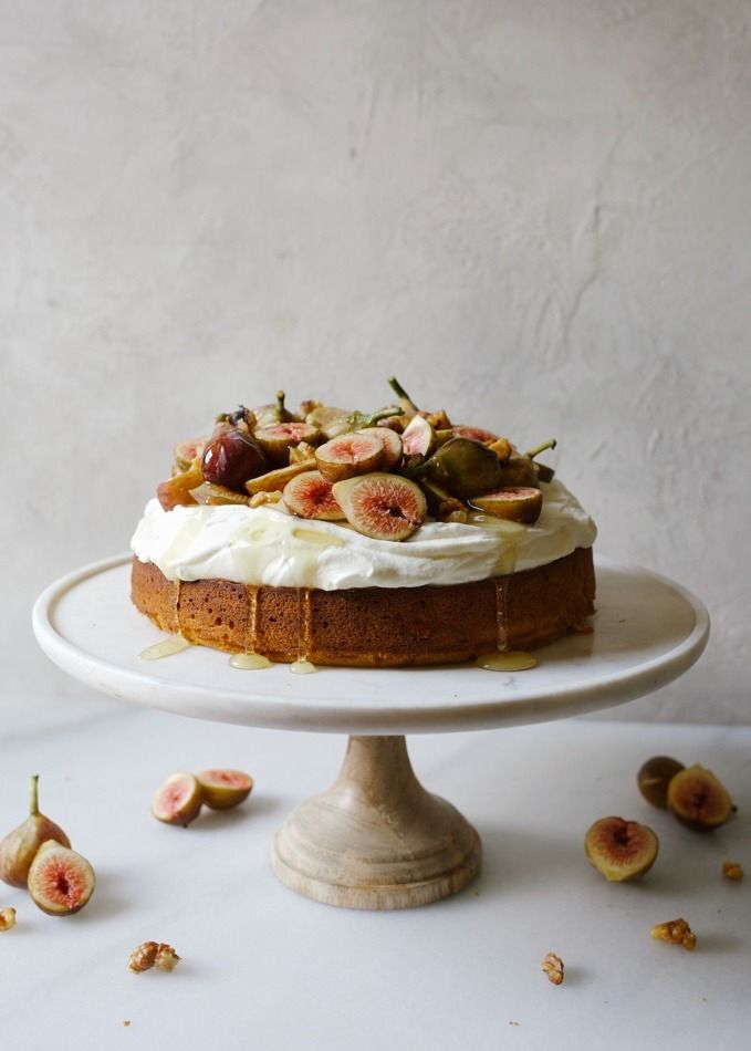 a cake sitting on top of a white plate covered in frosting and figs