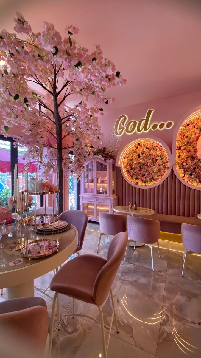 the interior of a fancy restaurant with pink chairs and flowers on the wall behind it