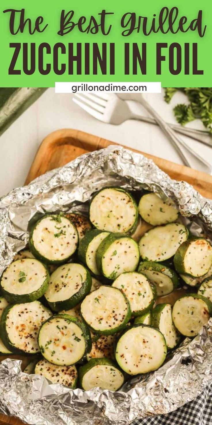 cooked zucchini in foil on a cutting board with fork and knife next to it