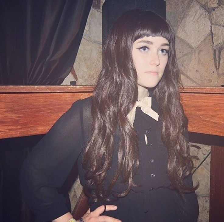 a woman with long hair standing in front of a fireplace