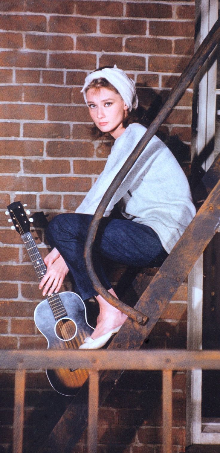 a woman is sitting on the stairs with her guitar