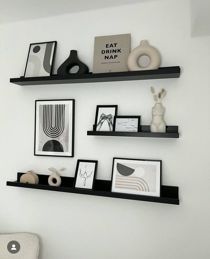 three black shelves with pictures and other items on them in a white walled living room