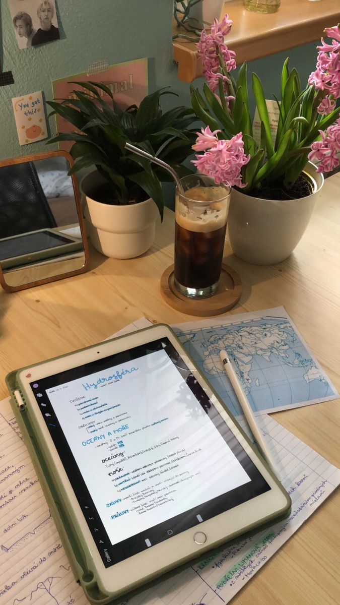 a tablet computer sitting on top of a wooden table next to a potted plant