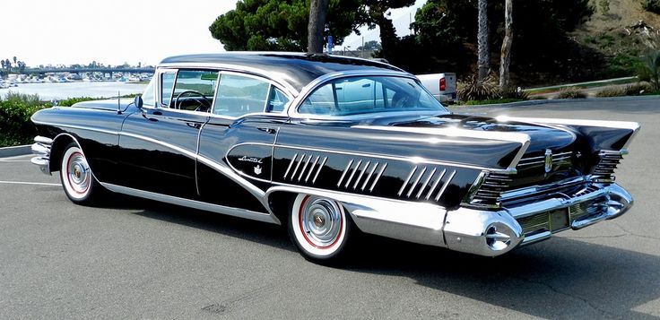 an old black car parked in a parking lot