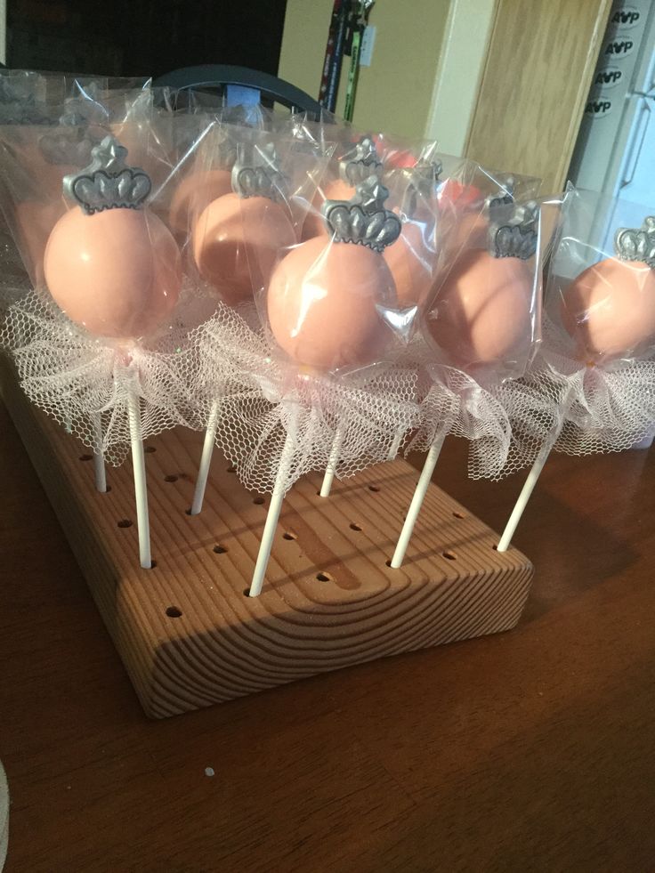 cake pops are wrapped in cellophane and placed on a wooden stand for display