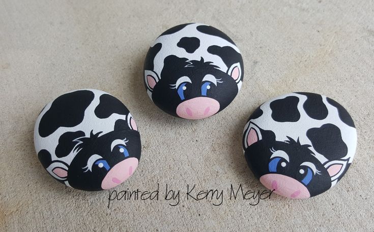 three black and white cows painted on rocks