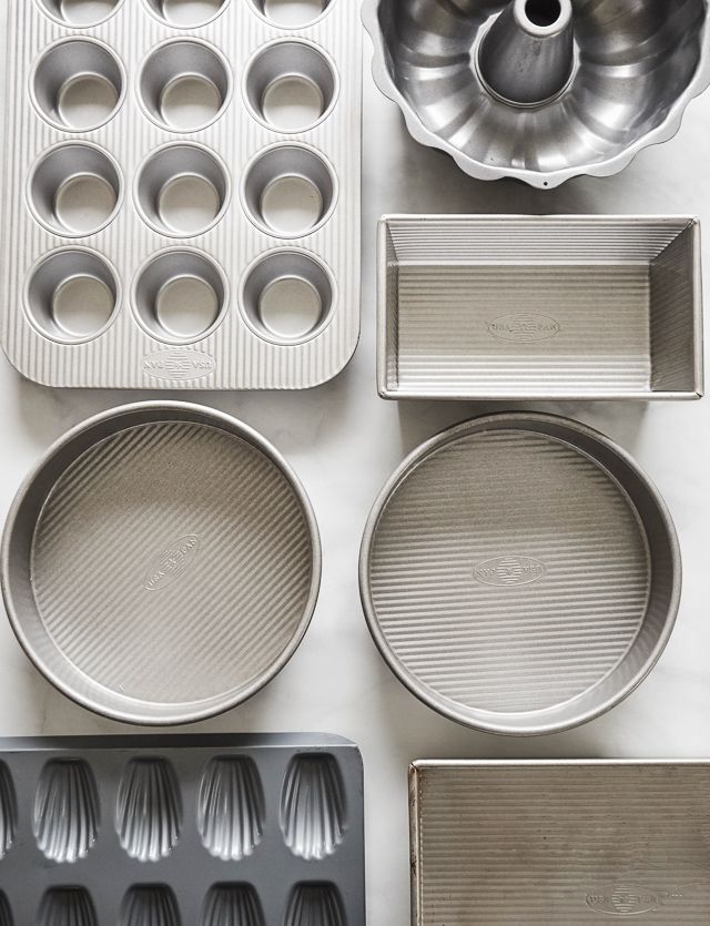 an assortment of baking utensils and pans laid out on a white surface