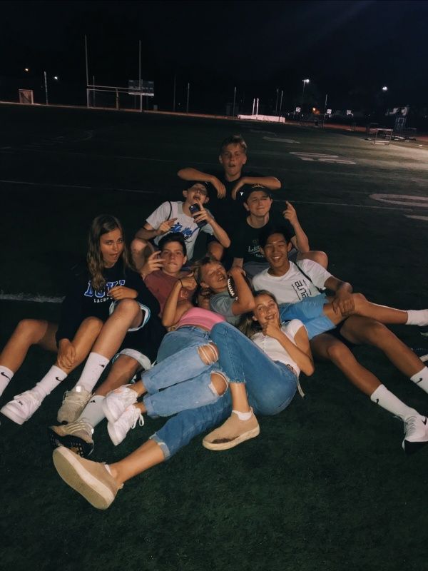 a group of young people sitting on top of each other in the middle of a field